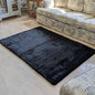 Black textured rug on a marble floor with a patterned sofa in the background.