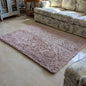 Pink rug on a marble floor with a patterned sofa in the background