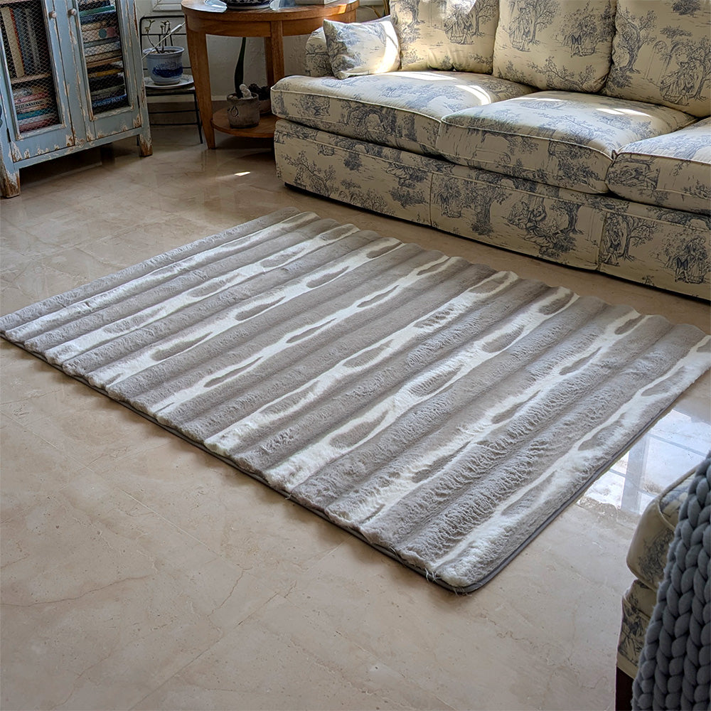 Gray striped rug on a beige floor with a patterned sofa in the background.