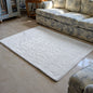 White textured rug on a marble floor with a patterned sofa in the background.