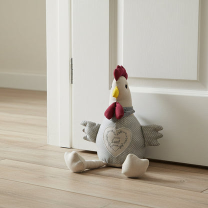 Stuffed rooster toy on a wooden floor in a room with white cabinets.