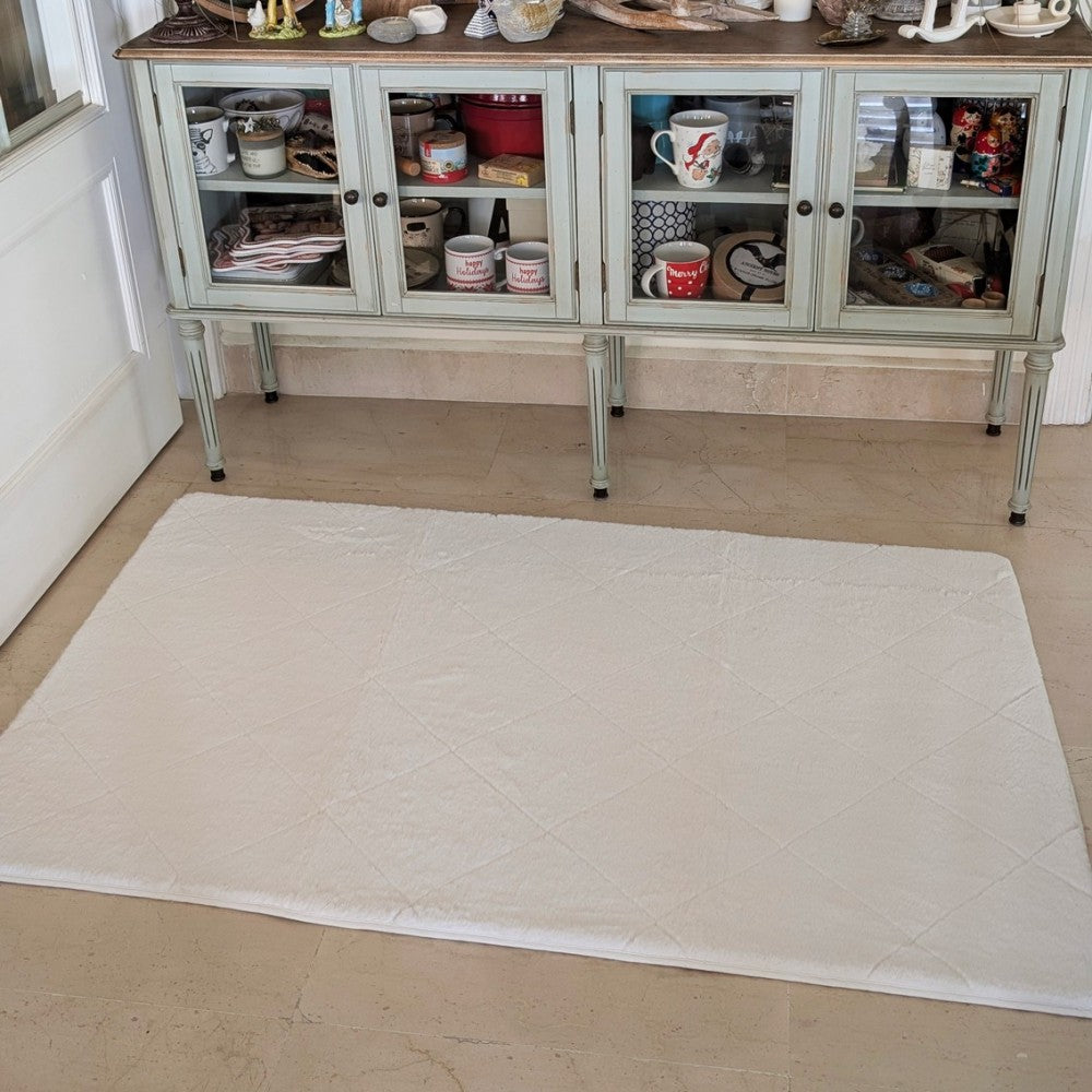 White quilted mat on a marble floor in front of a glass-fronted cabinet.