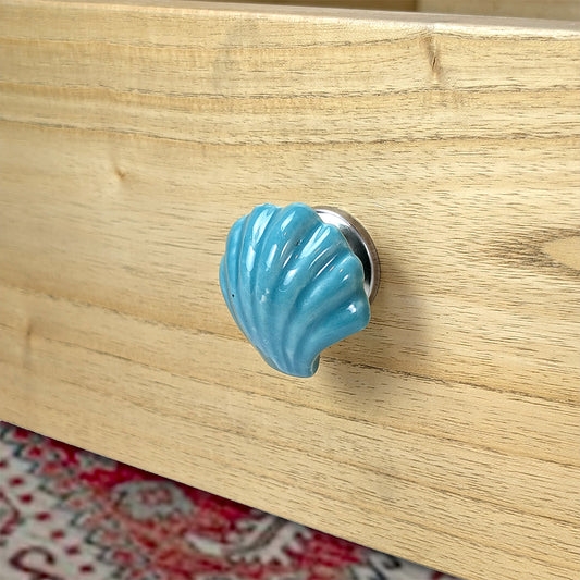 Blue shell-shaped knob on a wooden surface
